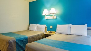 Ein Hotelzimmer mit zwei Betten, jeweils mit einer blau-beige Decke, weißen Kissen und einem Nachttisch mit Lampe und Telefon.