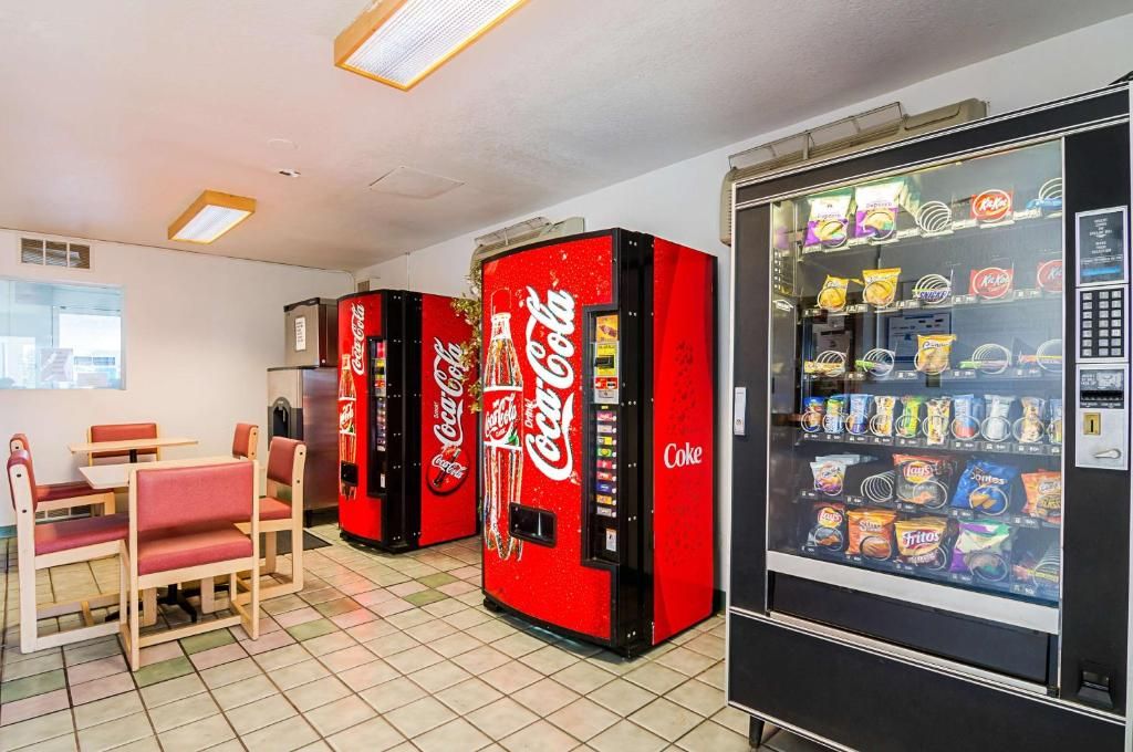 A room with three Coca-Cola vending machines and a snack vending machine.