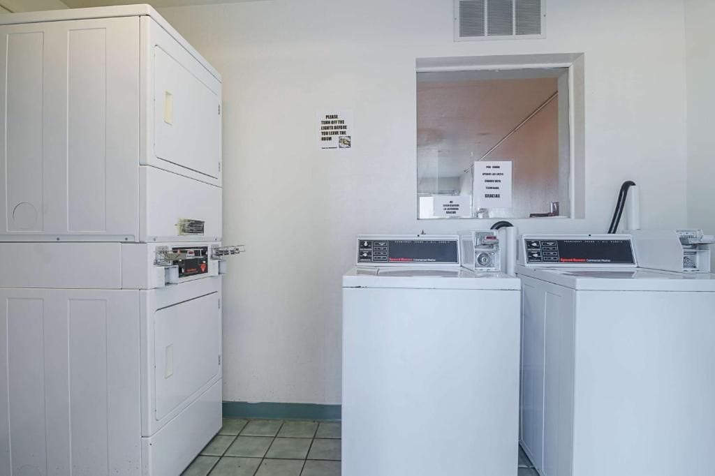 A laundry room with stacked dryers and a washing machine.