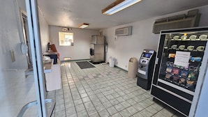 Ein sauberes, gefliesstes Badezimmer mit Kühlschrank, Mülleimern und einem Geldautomaten.