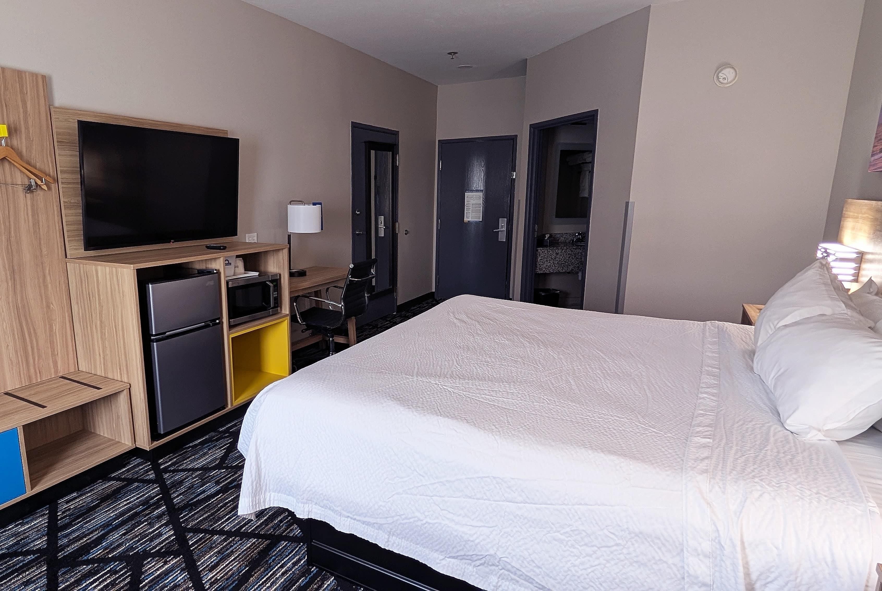 A hotel room with a bed, a television, a desk, and a wardrobe.
