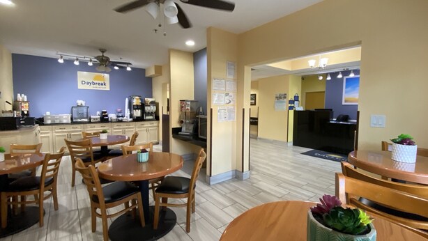 A breakfast area with wooden tables and chairs, a ceiling fan, and a coffee station. - Days Inn & Suites by Wyndham Augusta Near Fort Eisenhower (Grovetown)