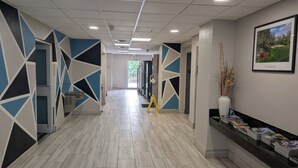A hallway with geometric wall designs, a reception desk with magazines, and a framed picture on the wall. - Days Inn & Suites by Wyndham Augusta Near Fort Eisenhower (Grovetown)