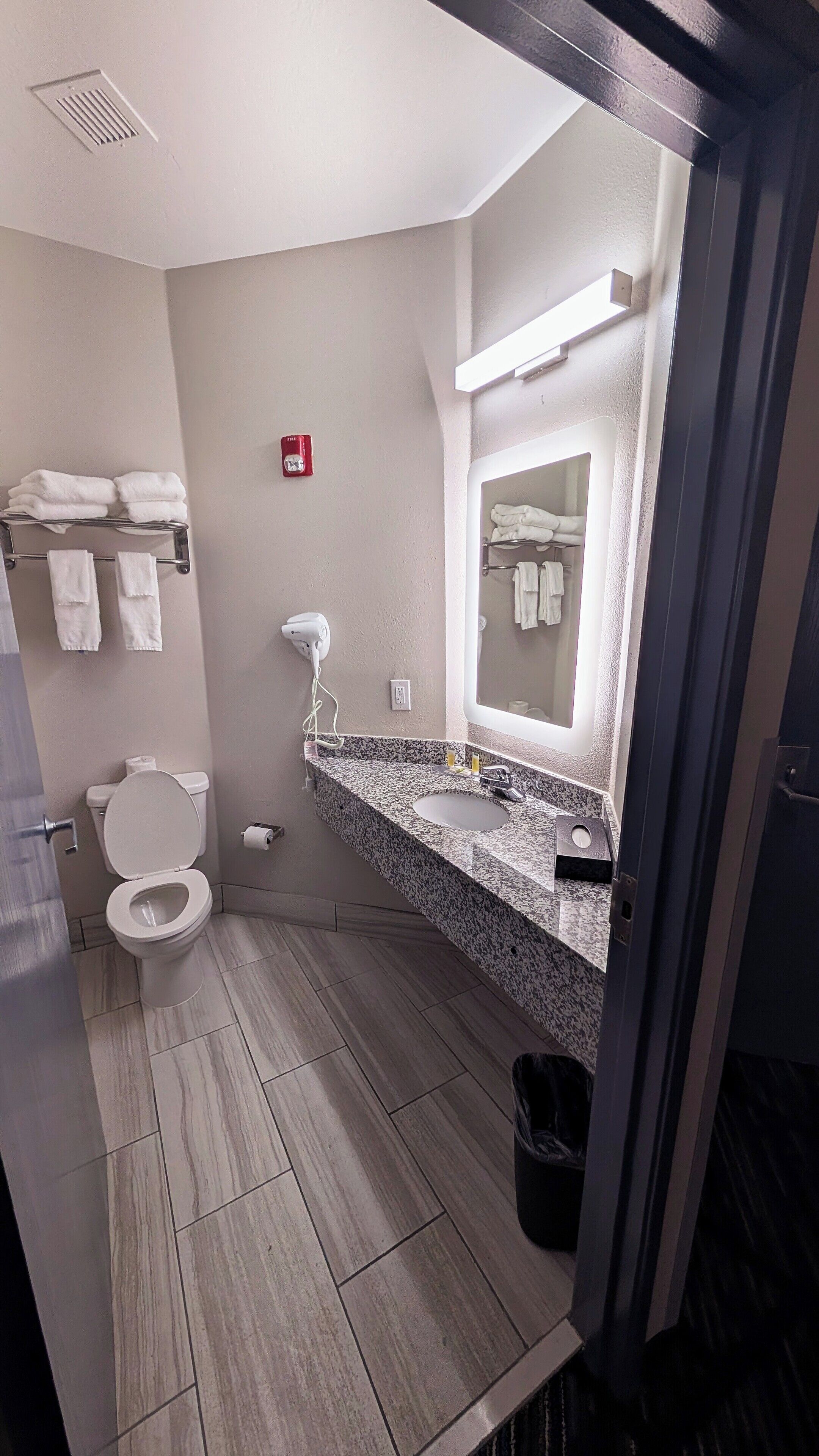 A bathroom with a toilet, sink, towel rack, and a mirror.