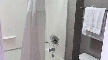 Een badkamer met een bad, douche, toilet en een handdoekhouder.