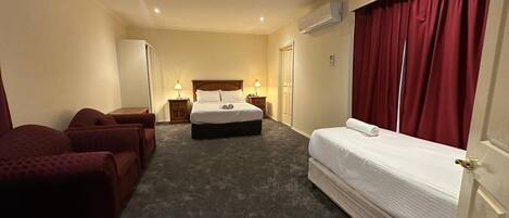 A hotel room with a bed, two bedside tables, a chair, a desk, and a wardrobe.