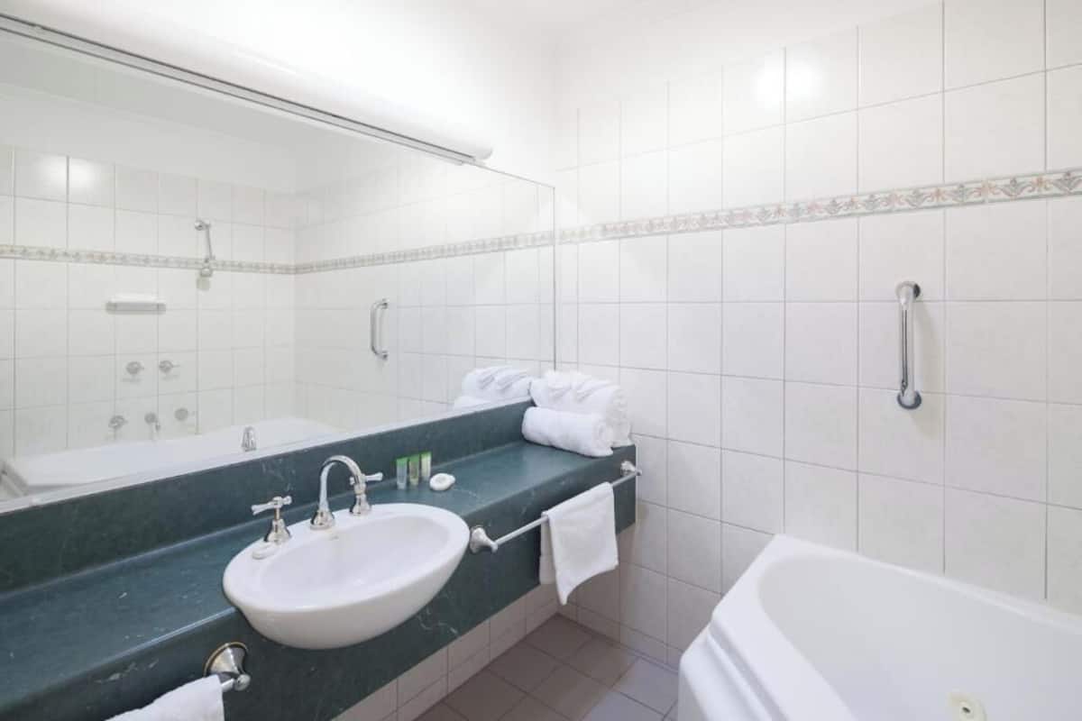 Ein Badezimmer mit Waschbecken, Spiegel, Handtuchhalter und Badewanne.