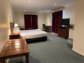A hotel room with a bed, a desk, a TV, a lamp, and a chair.