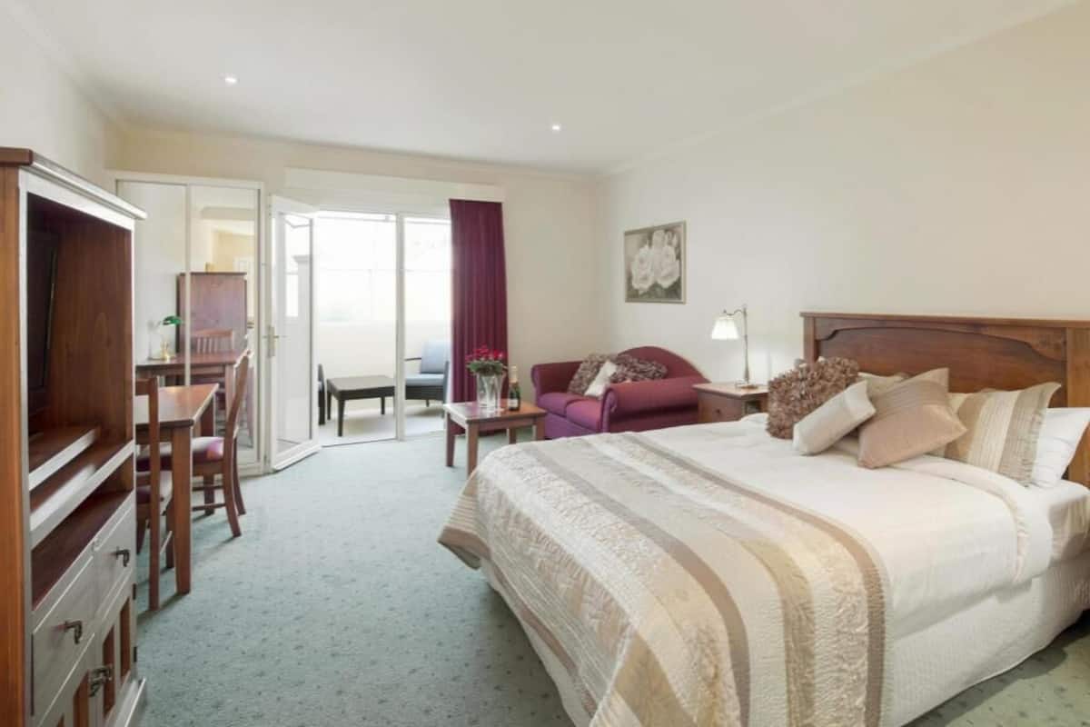 Ein Hotelzimmer mit Bett, Schreibtisch, Sessel, Sofa und einer Tür zum Balkon.