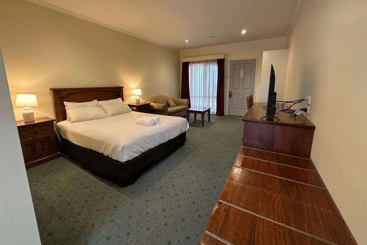 Ein Hotelzimmer mit Bett, Nachttischen, Schreibtisch, Stuhl und Fernseher.