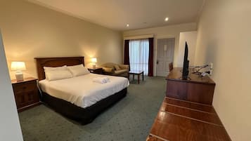 A hotel room with a bed, bedside tables, a desk, a chair, and a television.