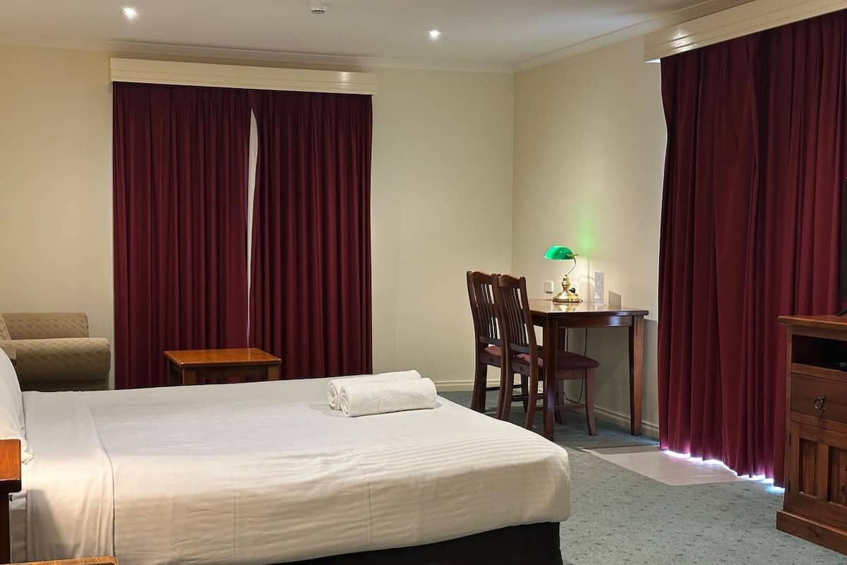 Ein Hotelzimmer mit Bett, Schreibtisch, Stuhl und einem kleinen Tisch.