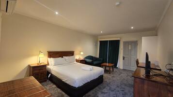 A hotel room with a bed, bedside tables, a desk, a chair, a television, and a door.