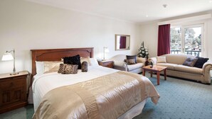 Una habitación de hotel con una cama grande, un sofá, una mesita de centro y una mesita de noche.