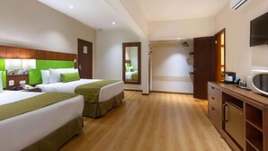 A hotel room with two beds, a desk, a mirror, and a TV.