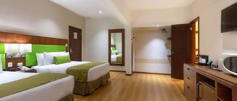 A hotel room with two beds, a desk, a mirror, and a TV.