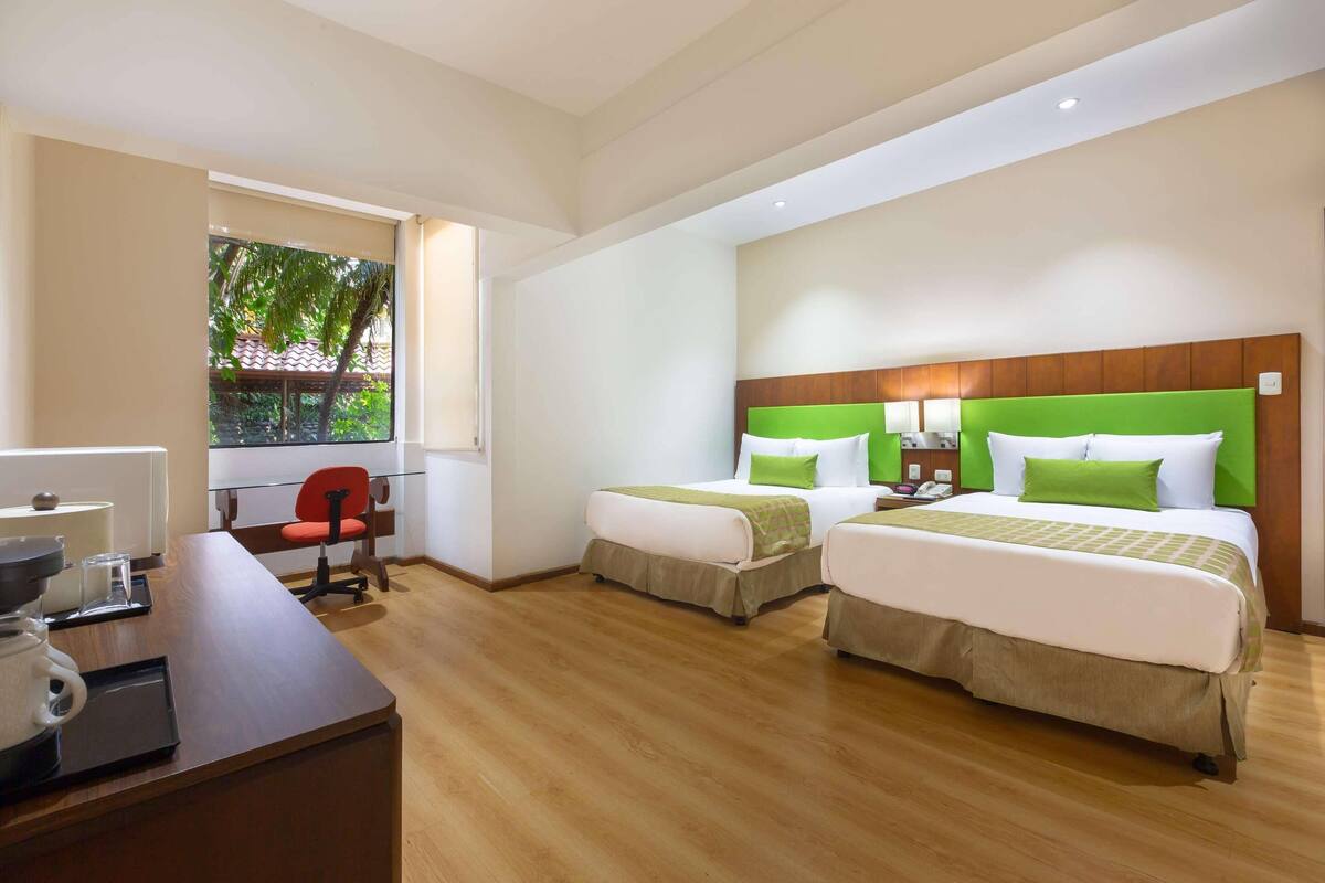Ein Hotelzimmer mit zwei Betten, einem Schreibtisch und einem Stuhl.