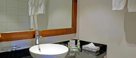 Un baño con lavamanos blanco, un espejo y un perchero para toallas.