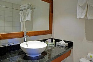 Un baño con lavamanos blanco, un espejo y un perchero para toallas.