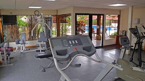 A gym with cardio equipment, weight machines, and a pool view.