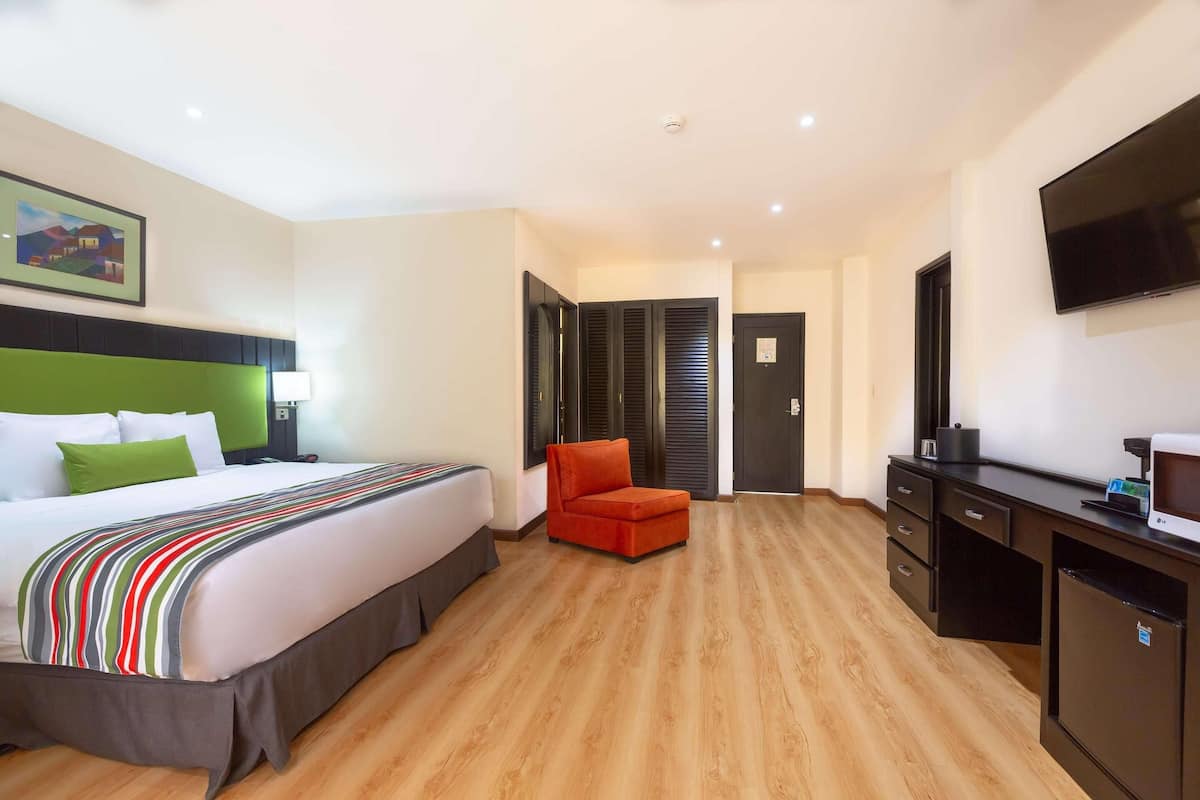 Ein Hotelzimmer mit Bett, Schreibtisch, Stuhl und Fernseher.
