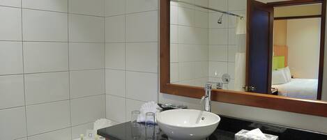 Un baño con lavamanos blanco, un espejo y un perchero para toallas.