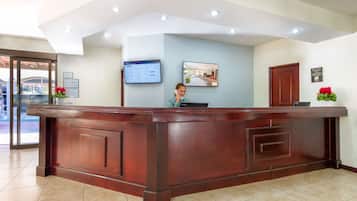 A reception desk with a computer monitor, a framed picture, and a wooden door.