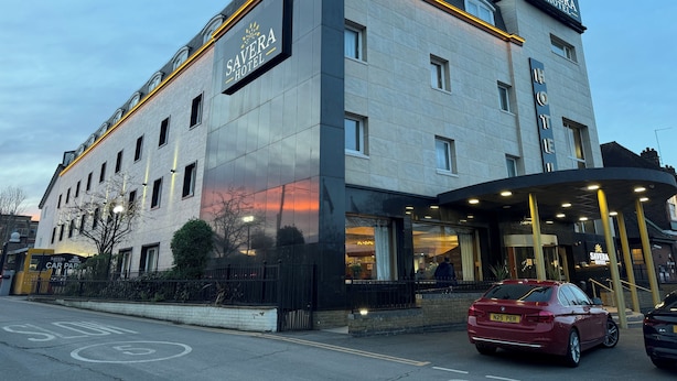 Een modern hotel met een opvallend bord, grote ramen en een goed verlichte ingang.