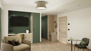 Una habitación de hotel moderna con sofá, una mesita redonda, un televisor de pantalla plana en la pared y una puerta de madera.