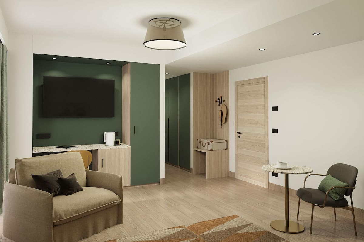 Una habitación de hotel moderna con sofá, una mesita redonda, un televisor de pantalla plana en la pared y una puerta de madera.