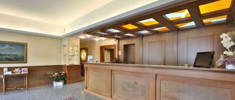 A reception area with a wooden reception desk, a clock, and a framed picture on the wall.