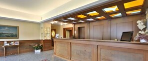 A reception area with a wooden reception desk, a clock, and a framed picture on the wall.