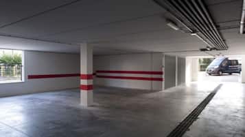 Amplio estacionamiento interior con pisos de concreto y líneas de seguridad rojas en las paredes.