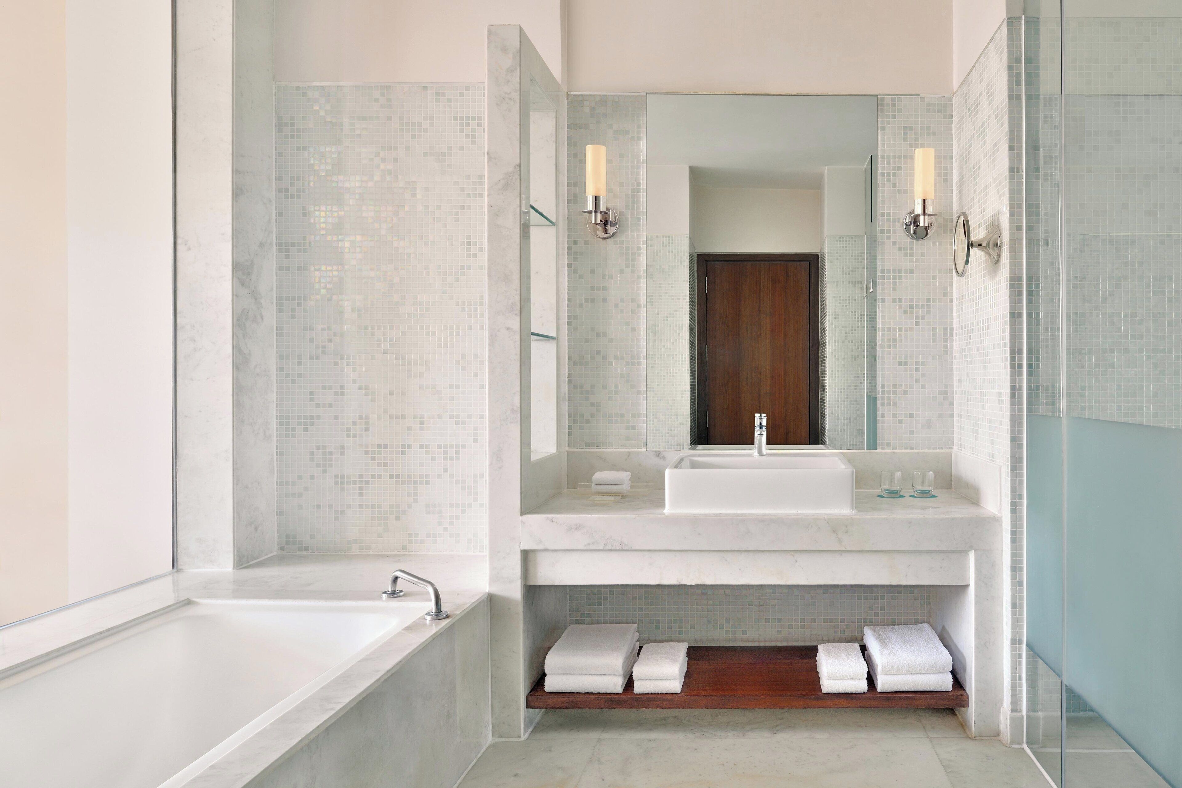 Un baño moderno con un espejo grande, dos lavamanos, una bañera y zona de ducha.