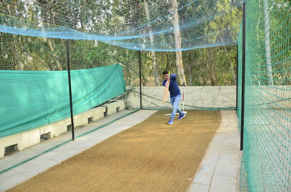 A cricket practice net with a player in blue attire. - Le Méridien Jaipur Resort & Spa (Amer)