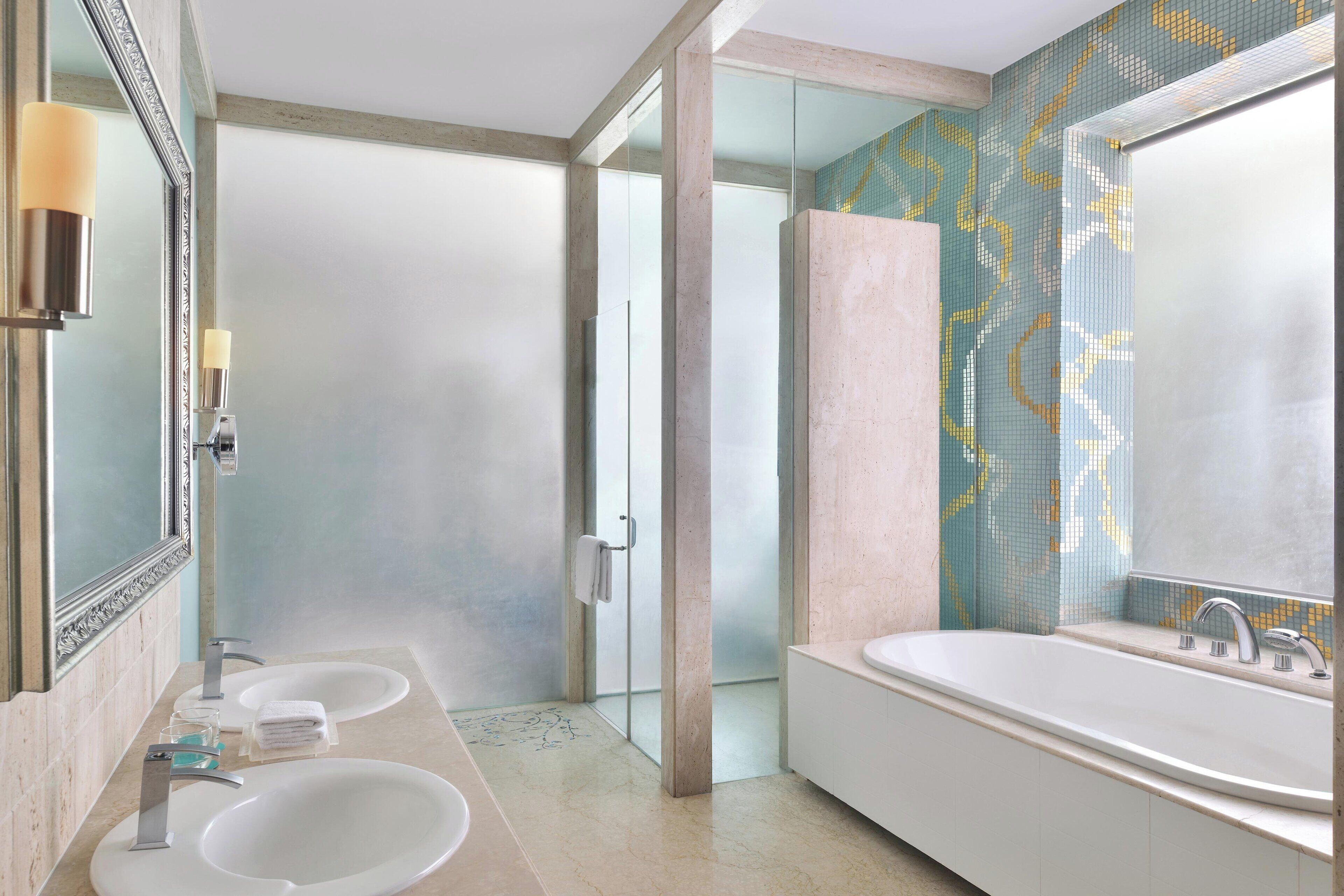 A modern bathroom with two sinks, a large bathtub, and a glass shower enclosure.