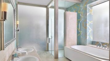 A modern bathroom with two sinks, a large bathtub, and a glass shower enclosure.