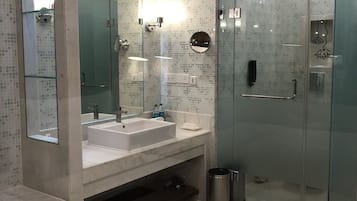 A modern bathroom with a glass-enclosed shower, two sinks, and a large mirror.