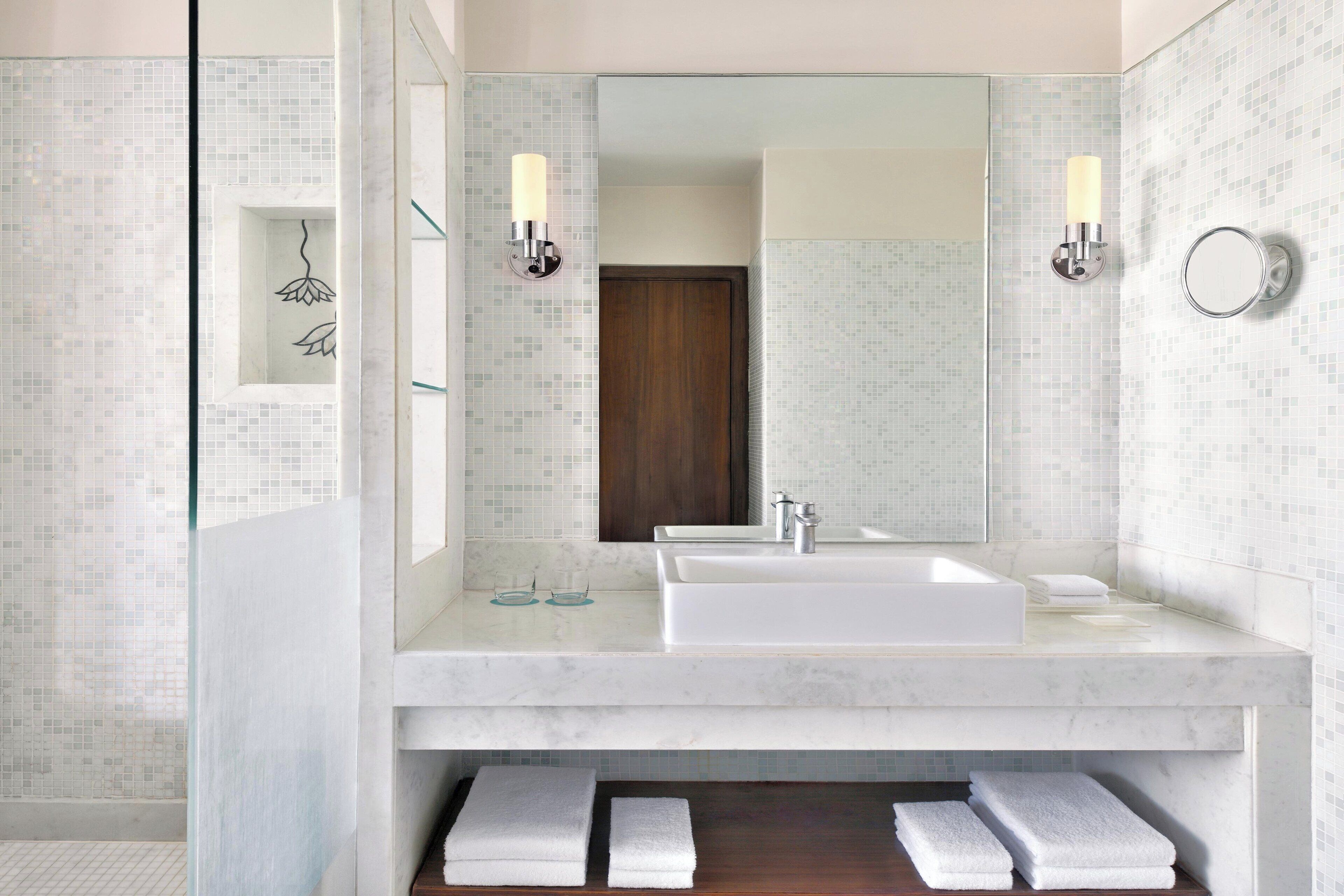 A modern bathroom with a large mirror, a white sink, and two wall-mounted lights.