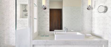 A modern bathroom with a large mirror, a white sink, and two wall-mounted lights.