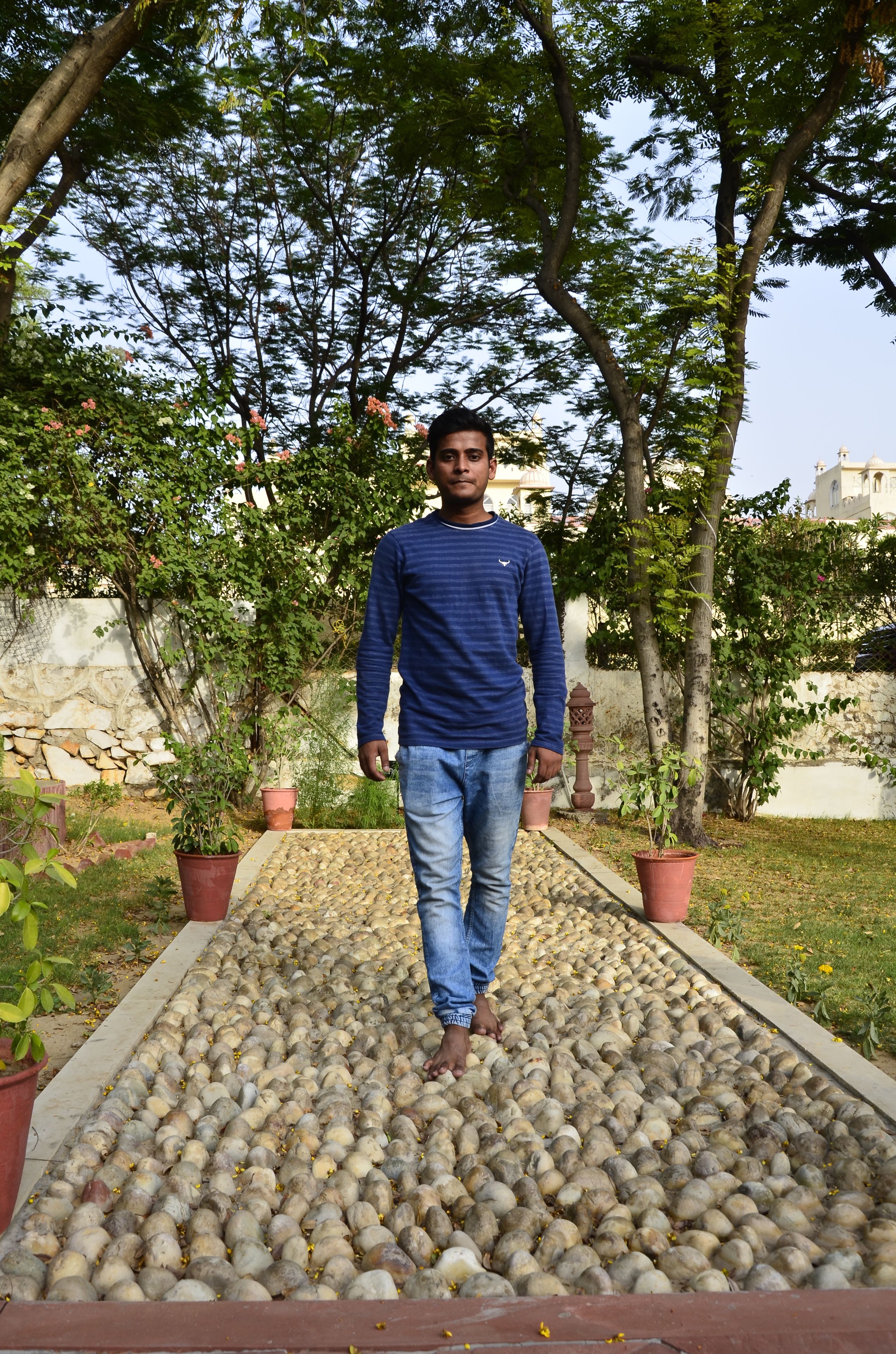 A man walking on a pathway lined with potted plants.