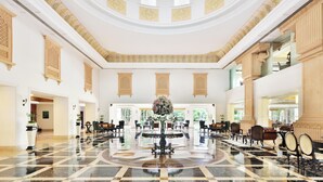 Eine geräumige Lobby mit einer zentralen Fontäne, hohen Decken und großen Fenstern.