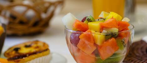 Ensalada de frutas en un bol de vidrio, con un muffin al fondo.