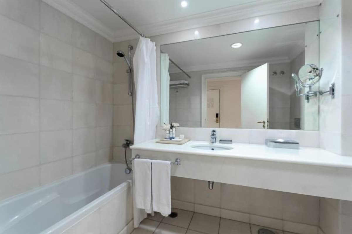 A modern bathroom with a bathtub, a sink, and a large mirror.