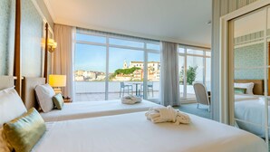 A hotel room with two beds, a balcony with a view of buildings, and a chair. - Olissippo Castelo (Lisbon)