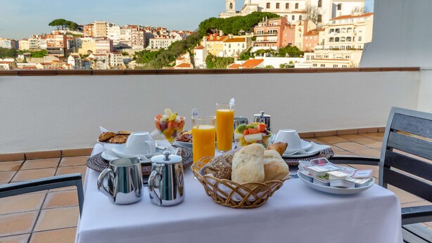 A breakfast table with a variety of food items and a view of a cityscape in the background. - Olissippo Castelo (Lisbon)