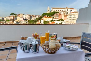 A breakfast table with a variety of food items and a view of a cityscape in the background. - Olissippo Castelo (Lisbon)