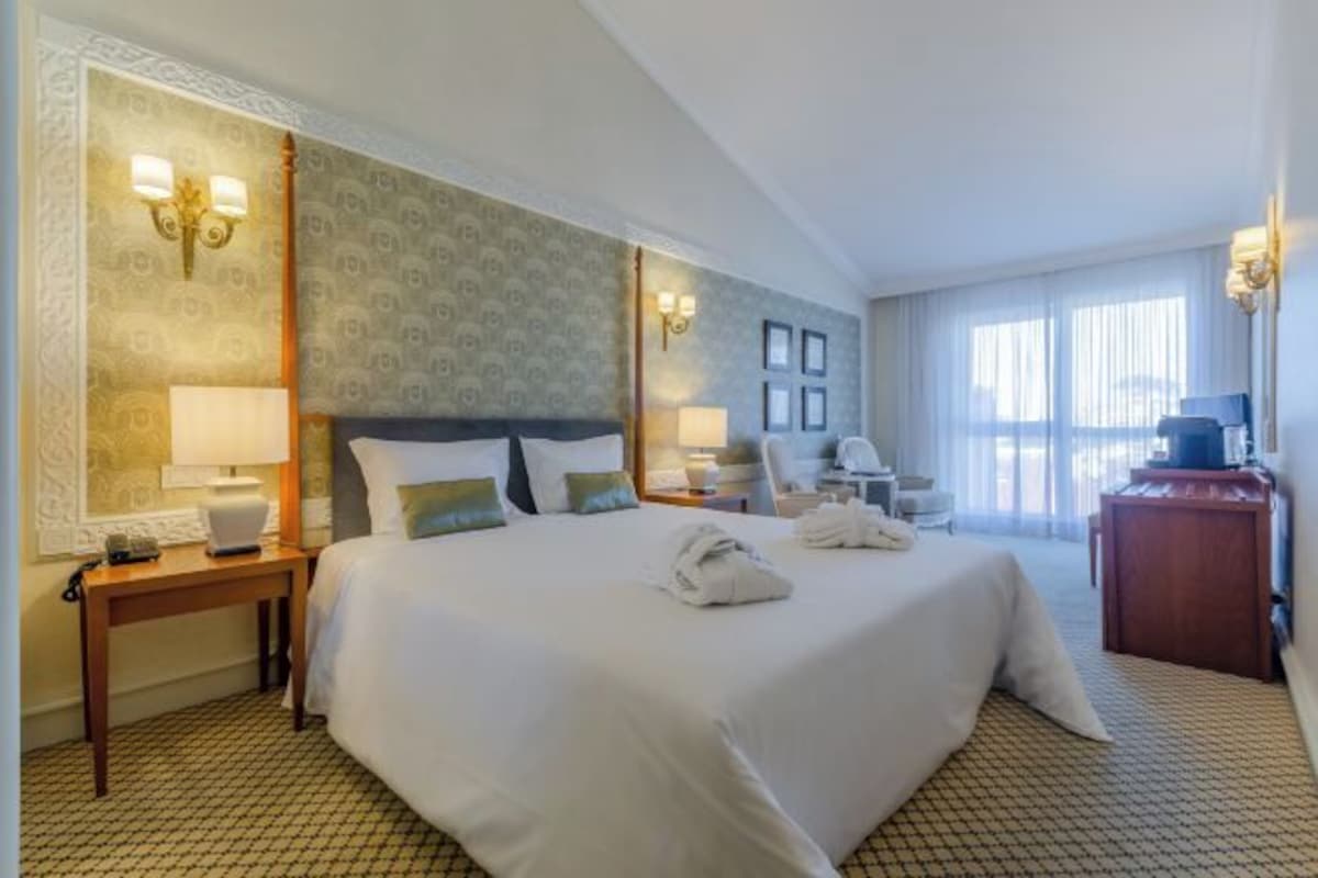 A hotel room with a large bed, two bedside tables, a desk, and a chair.