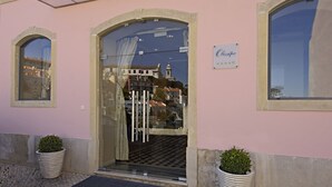 A building entrance with a glass door, a sign above it, and two potted plants on either side. - Olissippo Castelo (Lisbon)