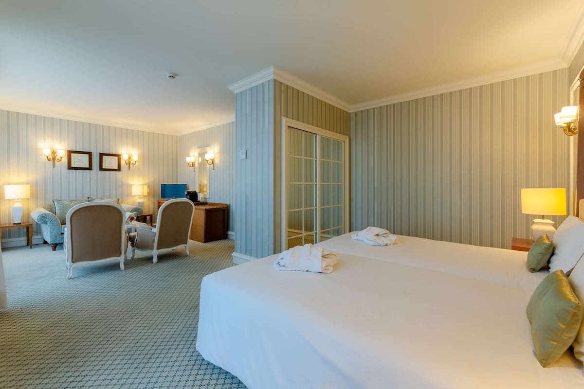Habitación de hotel con una cama grande, dos sillones, un escritorio y un armario.